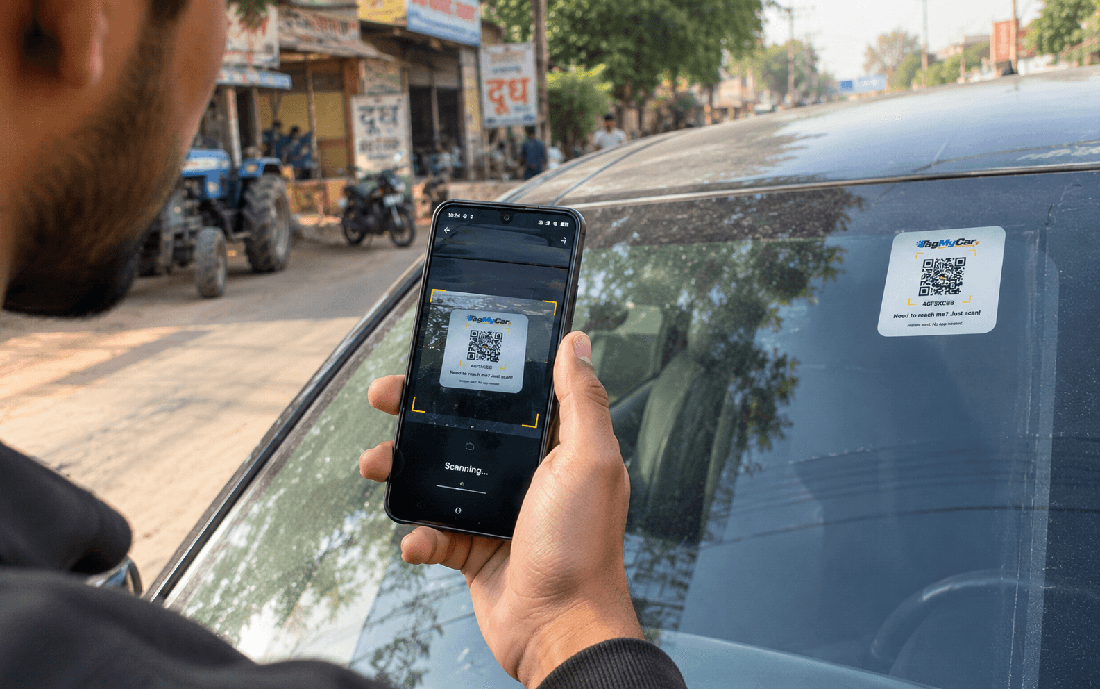 Ajay, a TagMyCar customer, scanning the TagMyCar QR tag on a car's rear windshield with his phone in a market lane