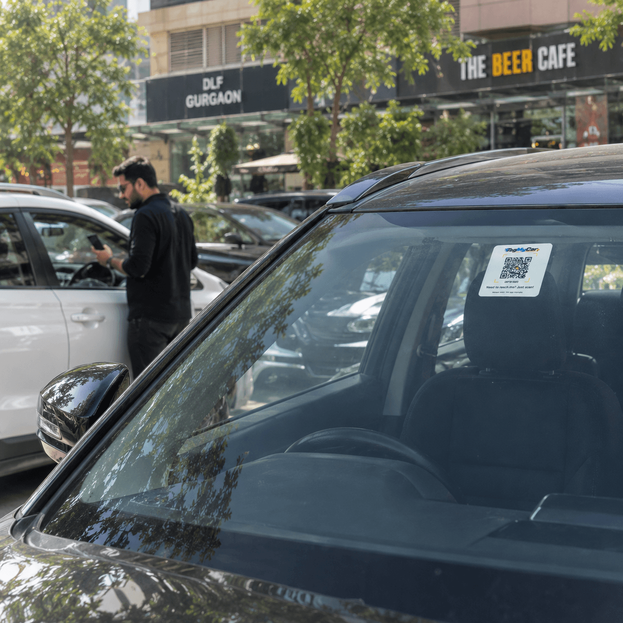 TagMyCar QR tag on the rear windshield of a car parked in a busy market parking lot